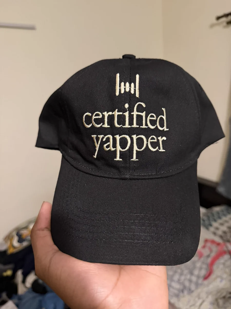 A black cap embroidered with the Flow mark and the words Certified Yapper